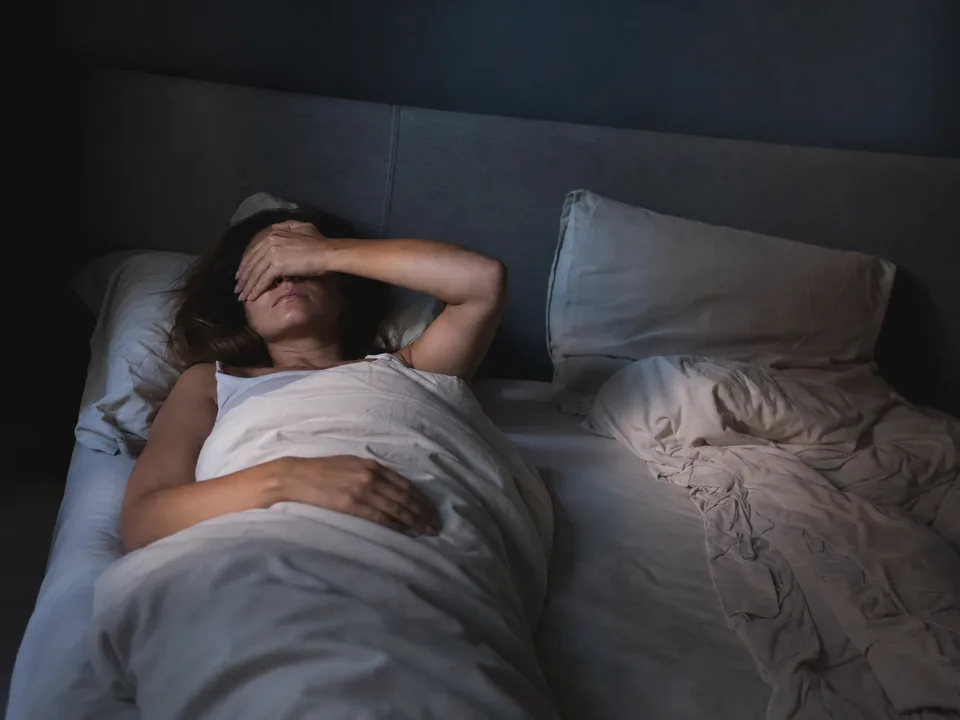 Erschöpfte Person nachts wach im Bett